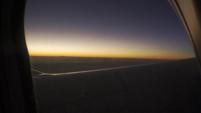 view through airplane window while flying over sunset sky landscape with twilight vanilla sky.sunset view from airplane window with wing creating a sense of adventure and wanderlust in travel