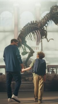Vertical Screen: Natural History Museum With a Father and Young Son Holding Hands, Watching and Learning About a Giant T-rex Dinosaur Skeleton. Family Vacation Fun and Education