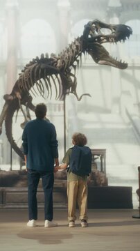 Vertical Screen: Natural History Museum With a Father and Young Son Holding Hands, Watching and Learning About a Giant T-rex Dinosaur Skeleton. Family Vacation Fun and Education