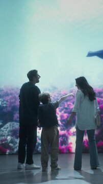 Vertical Screen: Oceanarium Marine Life Park:  Mom, Dad and Child Look at a Swimming Orca, Watching and Learning About Marine Life and Ocean Life. Cheerful Family Vacation Educational Trip