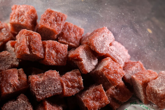 Frozen beef chunks for dog food with rich red color and frosty texture, perfect for pet nutrition and feeding. These small meat cubes provide healthy protein source for dogs