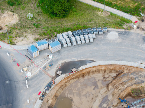 Aerial view of a new road construction site with stacks of paving stones, excavated earth, and construction materials in Riga, Latvia.