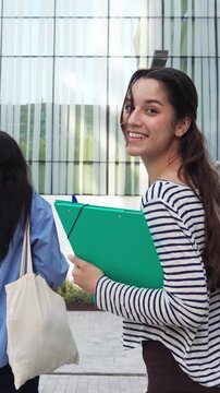 Happy female student smiling at camera while walking
