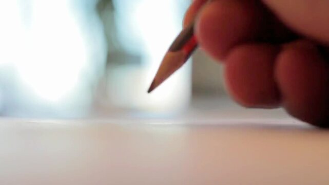 Close-up of a hand writing on white paper with a pencil and then flipping it to erase a mistake
