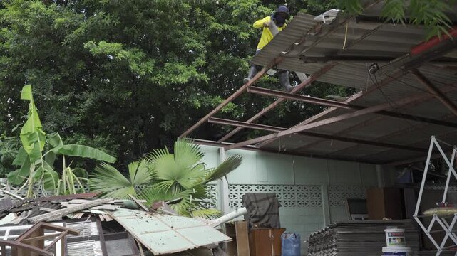 view to roof while worker dismantle demolish the roof in hot summer daytime, worker deconstruction the garage's roof