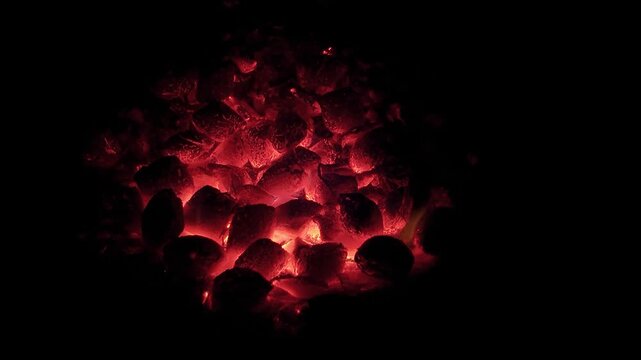 Gros plan sur un coeur de brasero rempli de braises incandescentes et de flammes vives.