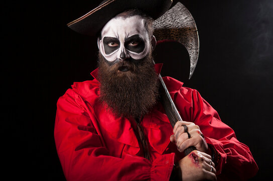 Medieval captain holds an axe while standing over a black background, wearing a Halloween outfit with a dramatic pirate style with theatrical pirate detail.