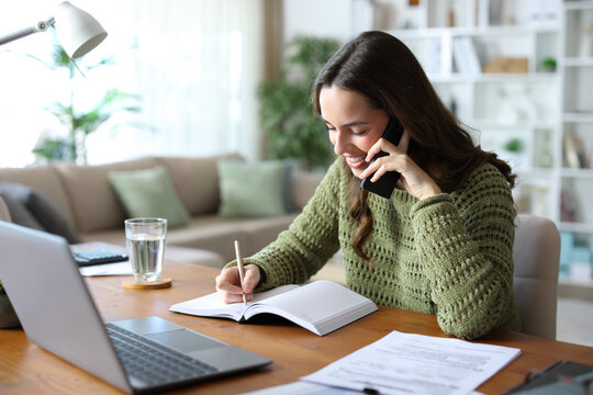 Happy teleworker talking on phone and scheduling an appointment