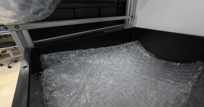 Close-up of a gloved hand wrapping a product with bubble wrap for safe packaging. Concept of shipping, protection, logistics, packaging, and product safety.