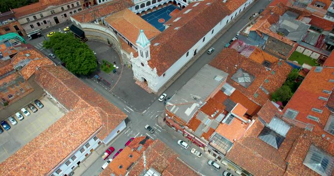 cinematic drone flying backward directly above la merced church in cuenca ecuador revealing the historic city skyline and beautiful colonial architecture in the background on a clear sunny day