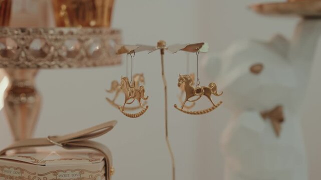 Gold rocking horse carousel ornament hanging on a stand beside a decorative favor box at a christening