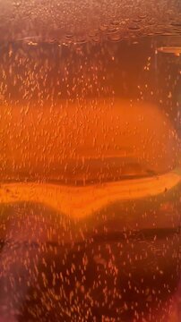 Macro shot of beer bubbles rising up in glass, close up carbonation texture of refreshing carbonated soda drink or champagne