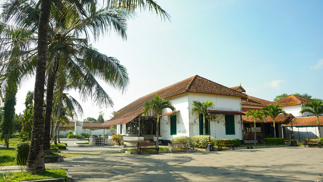 Old historical colonial building with traditional Javanese architecture and coconut trees under a clear blue sky, Indonesia.