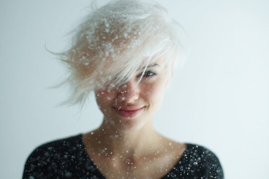 Rebel trickster woman portrait with platinum hair and shy smile with floating snow sparks for minimalist background and banner design