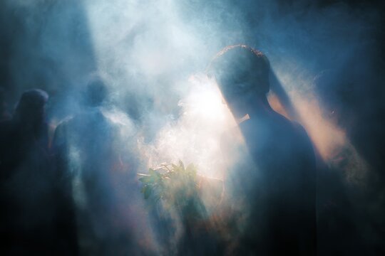 Shamanic smoke ritual with silhouetted figures in dramatic backlight and mist for spiritual ceremony background and healing atmosphere design
