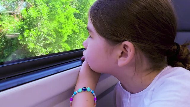 Side view of a sad and bored young girl looking out the window of a moving train during a long journey. High quality 4k footage