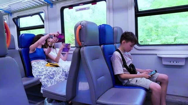 A mother with her children as passengers inside a train car, taking a selfie and using smartphones during a family travel journey. High quality 4k footage