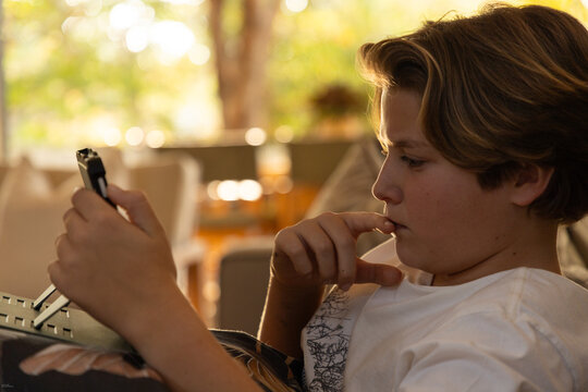 close up profile of young boy using tablet computer at home at sunset