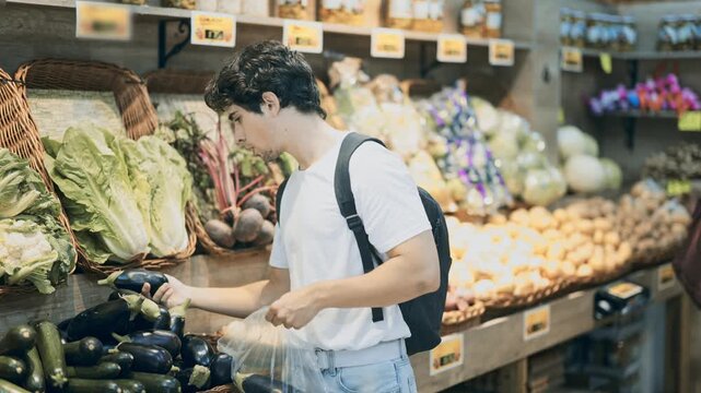 Man shopping, examine vegetable in store and buy elect eggplant. Self-service store, organic vegetables and fruits from all over world