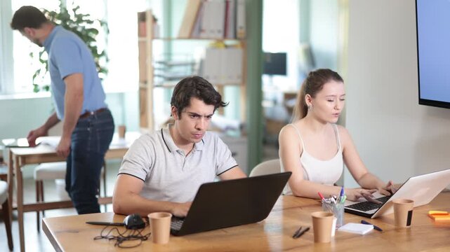 Man and girl staff colleagues working at laptop computer in office room space. Day in office of business structure, manager working at computer. Hard work, multitasking, efficient execution of tasks