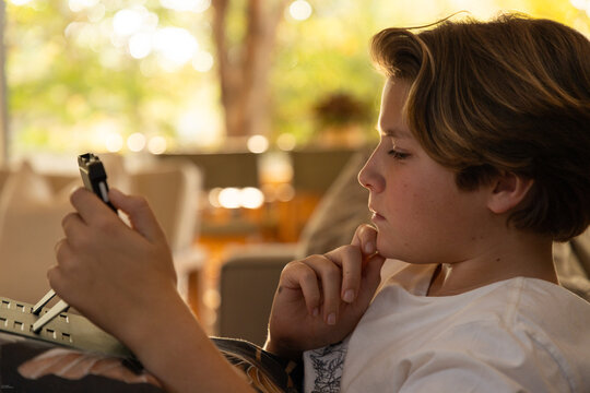 close up profile of young boy using tablet computer at home at sunset