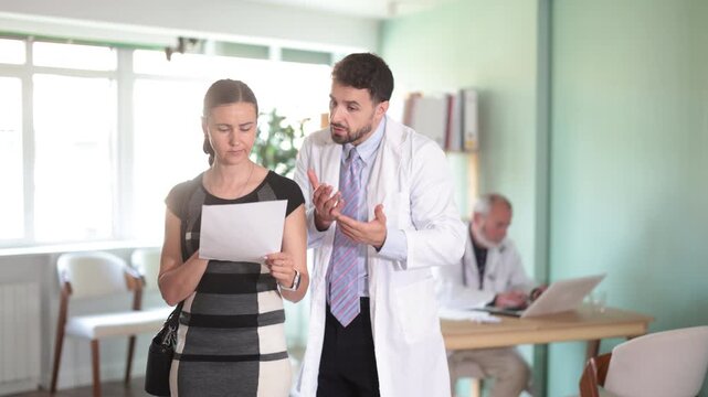Male doctor and sad woman patient examine papers, discuss medical test. Specialist interprets tests, tells you action plan to achieve goals of treatment. 