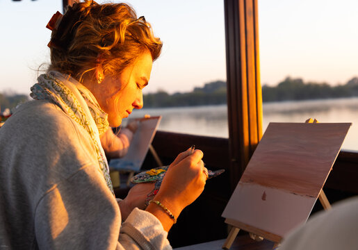 artists painting on vintage boat at sunrise, Zambezi River, Zambia, Africa