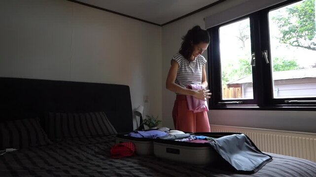 woman packing clothes into a suitcase for a trip