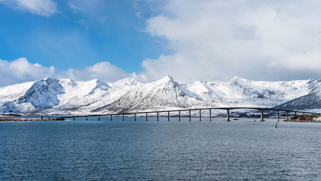 Landscape in the Vesteralen islands in Norway with snow covered mountains and blue sky, seen from the water