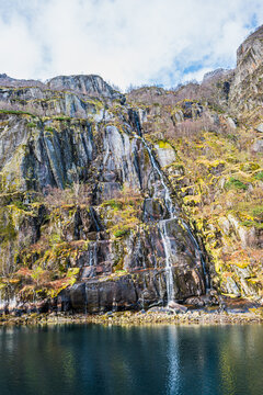 Steep rock face with a waterfall in Trollfjord in Norway