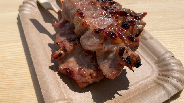mu ping or marinated grilled pork skewer thai street food on a disposable paper plate close up
