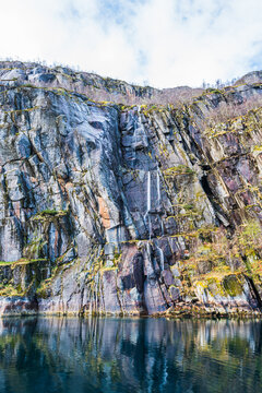 Steep rock face with a waterfall in Trollfjord in Norway