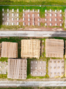 Aerial view of timber supply chain and sustainable forestry with stacked wooden logs and concrete blocks in a storage yard in Latvia.