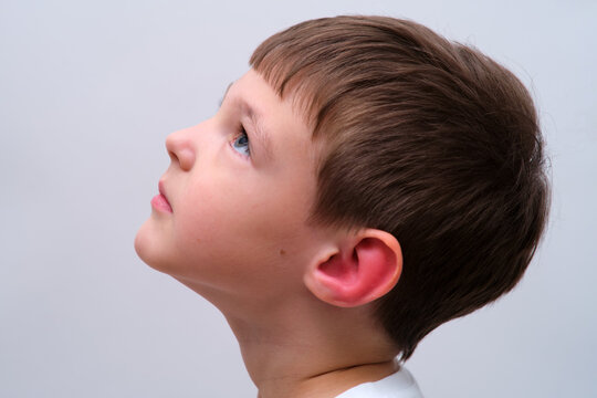Child with red swollen ear. Close-up portrait of boy suffering from inflammation and pain. Pediatric health and otitis media diagnosis concept for medical clinic and healthcare study.