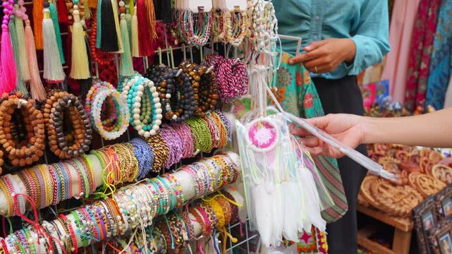 A woman shopping for handmade bracelets and colorful souvenirs at a local market near Borobudur Temple, Indonesia. Authentic travel, culture, craftsmanship, and tourism experience