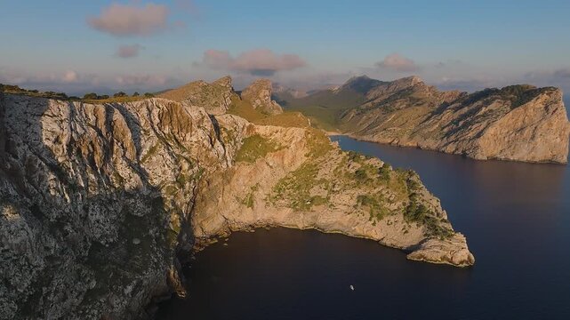 Mallorca, Spain - 4K Flying by Cap de Formentor at sunrise with amazing golden coloured cliffs and colorful clouds at background