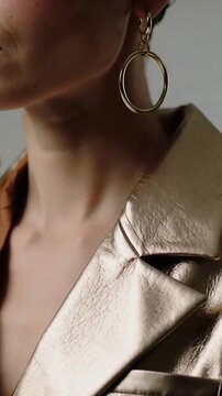 Vertical video: Starting turn model showing right neck in studio, highlighting gold hoop and jacket