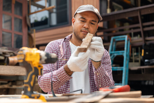 Portrait carpenter man working on DIY woodworking project at home workshop. Skilled craftsman using tools for handmade furniture, home improvement and sustainable lifestyle concept.