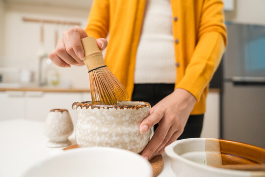 Asian women are brewing their own matcha tea at home for health benefits. Matcha is a healthy drink with reduced sugar content.