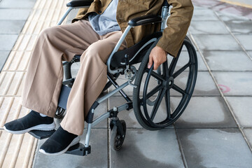 Fototapeta premium A man with a leg disability who cannot walk uses a wheelchair and travels by the train at a station He walks along the sidewalk where there are signs indicating accessibility for disabled individuals