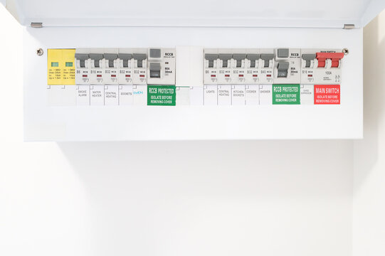 Close-up of a newly installed electrical distribution and safety panel showing individual circuit breakers and the red coloured mains electric cut off switch. Seen in a newly renovated apartment.