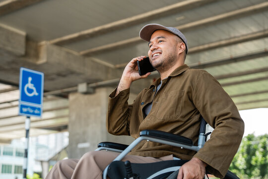 A man with a leg disability uses a wheelchair travels by train at  station walks along sidewalk signs indicating accessibility for disabled individuals Phone navigation calling a transport vehicle.