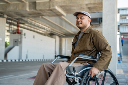 A man with a leg disability who cannot walk uses a wheelchair and travels by the train at a station He walks along the sidewalk where there are signs indicating accessibility for disabled individuals