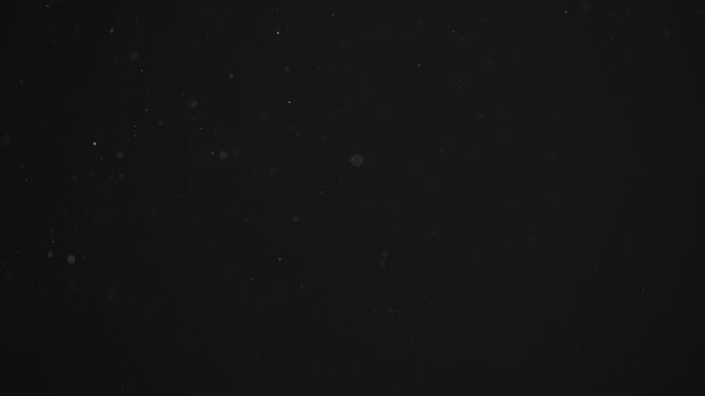Floating dust particles over dark background with shallow focus