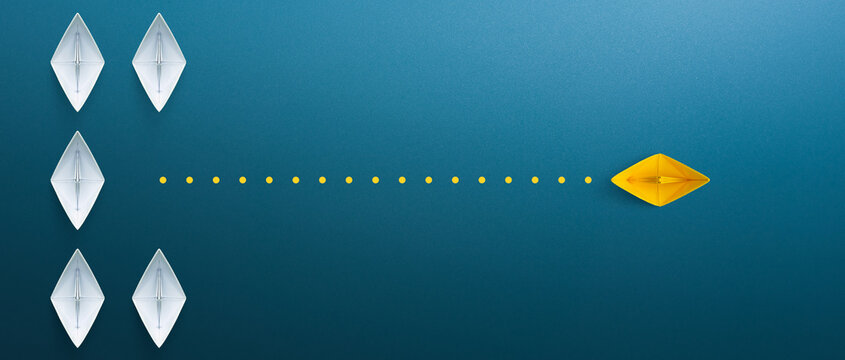 Business for innovative solution concept. Group of white paper ship in one direction and one yellow paper ship pointing in different way on blue background.