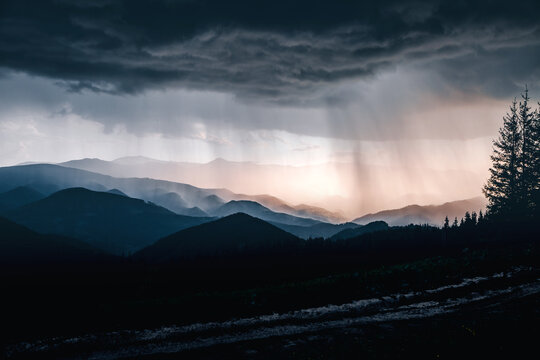 Dark clouds gather over the mountains as the rain begins at dusk, creating a spectacular landscape.
