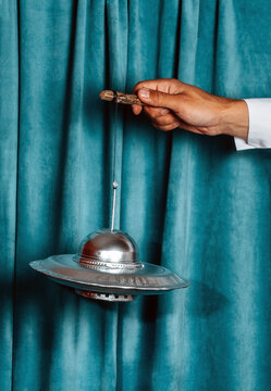 Hand holding a toy UFO on a string against a velvet curtain