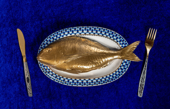 A golden fish on a plate symbolizes luxury lifestyle