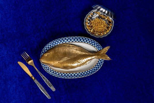 Golden fish and caviar on blue velvet symbolizing luxury and inflation