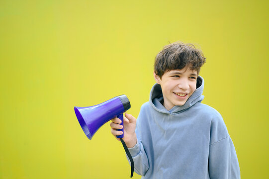 Boy holding a purple megaphone and smiling against a yellow background